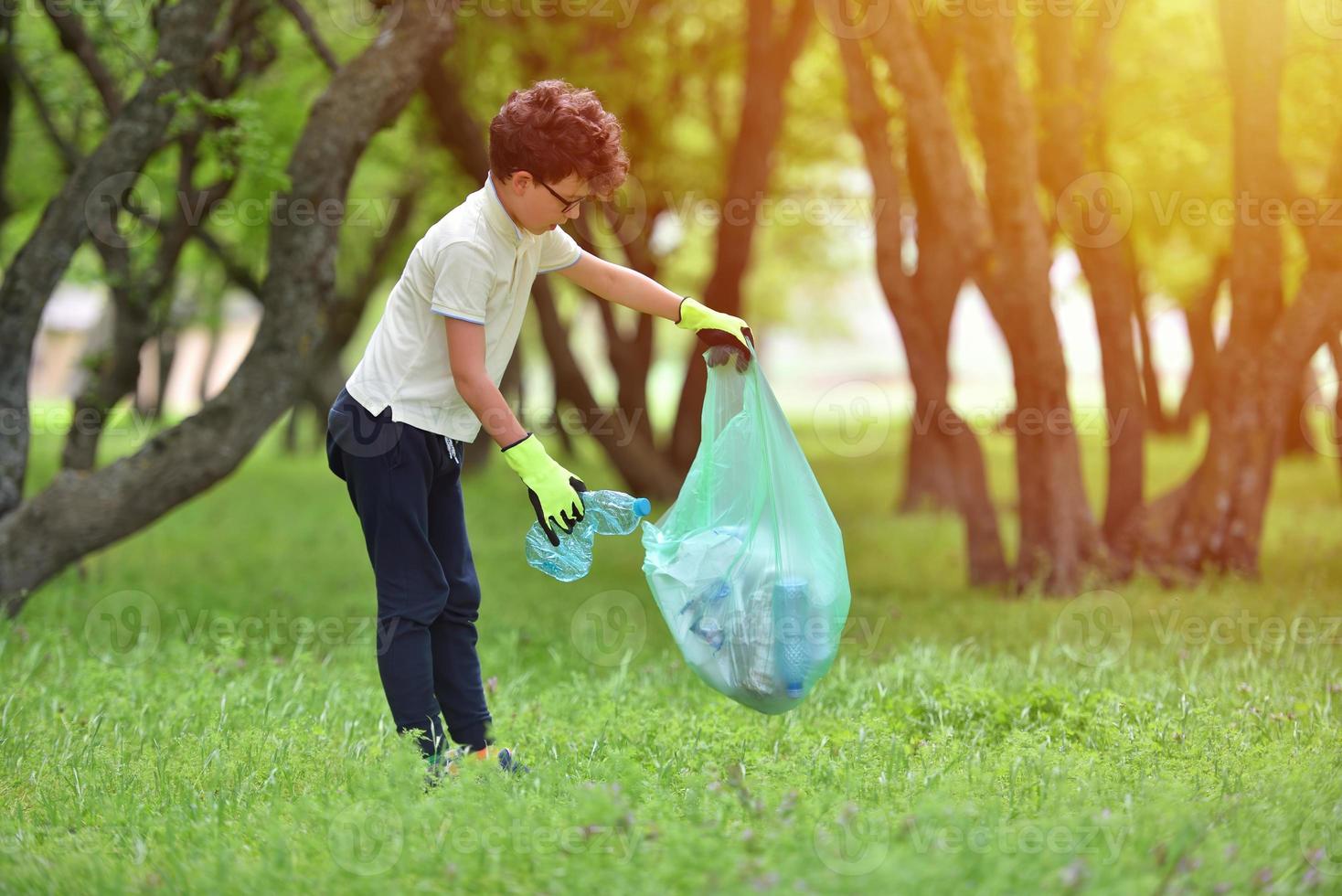 giovane ragazzo raccoglie spazzatura in una foresta di primavera al tramonto foto