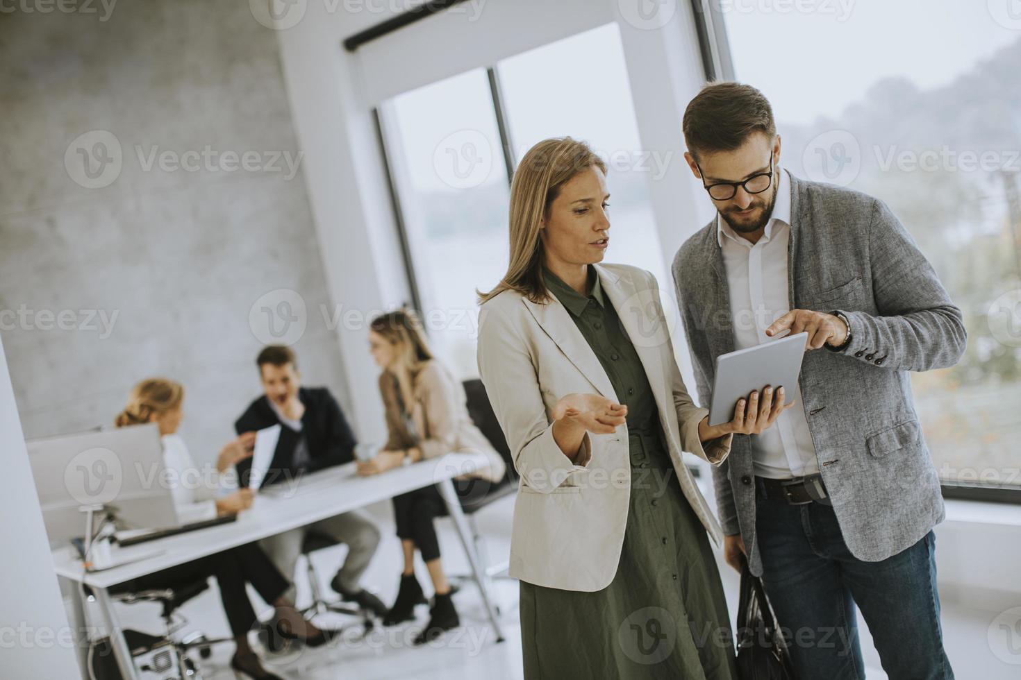 uomo e donna che guardano un tablet in un ufficio foto