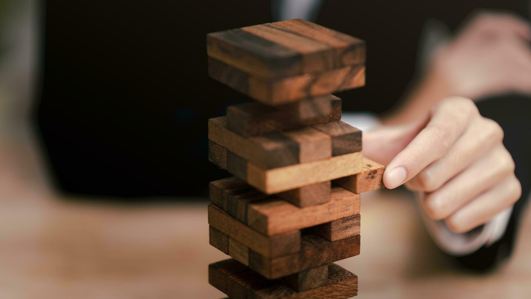 uomo d'affari traino un' jenga di legno scatola ,protezione e rischio gestione ,colpa protezione ,finanziario equilibrio ,finanziario rischio gestione concetto ,protezione di attività commerciale interessi ,attività commerciale decisione foto