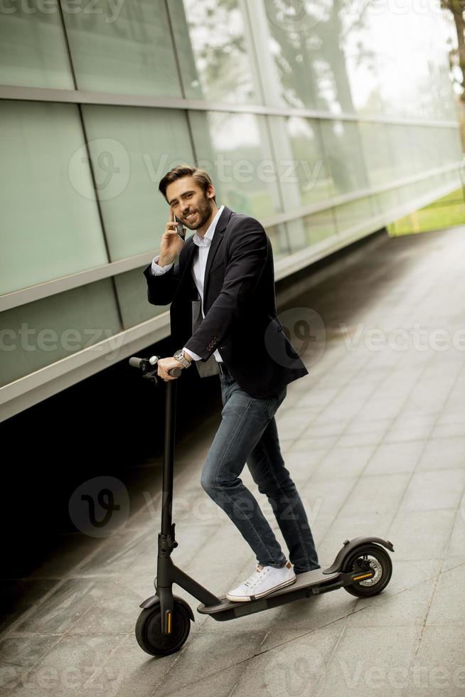 uomo che cavalca scooter mentre parla al telefono foto