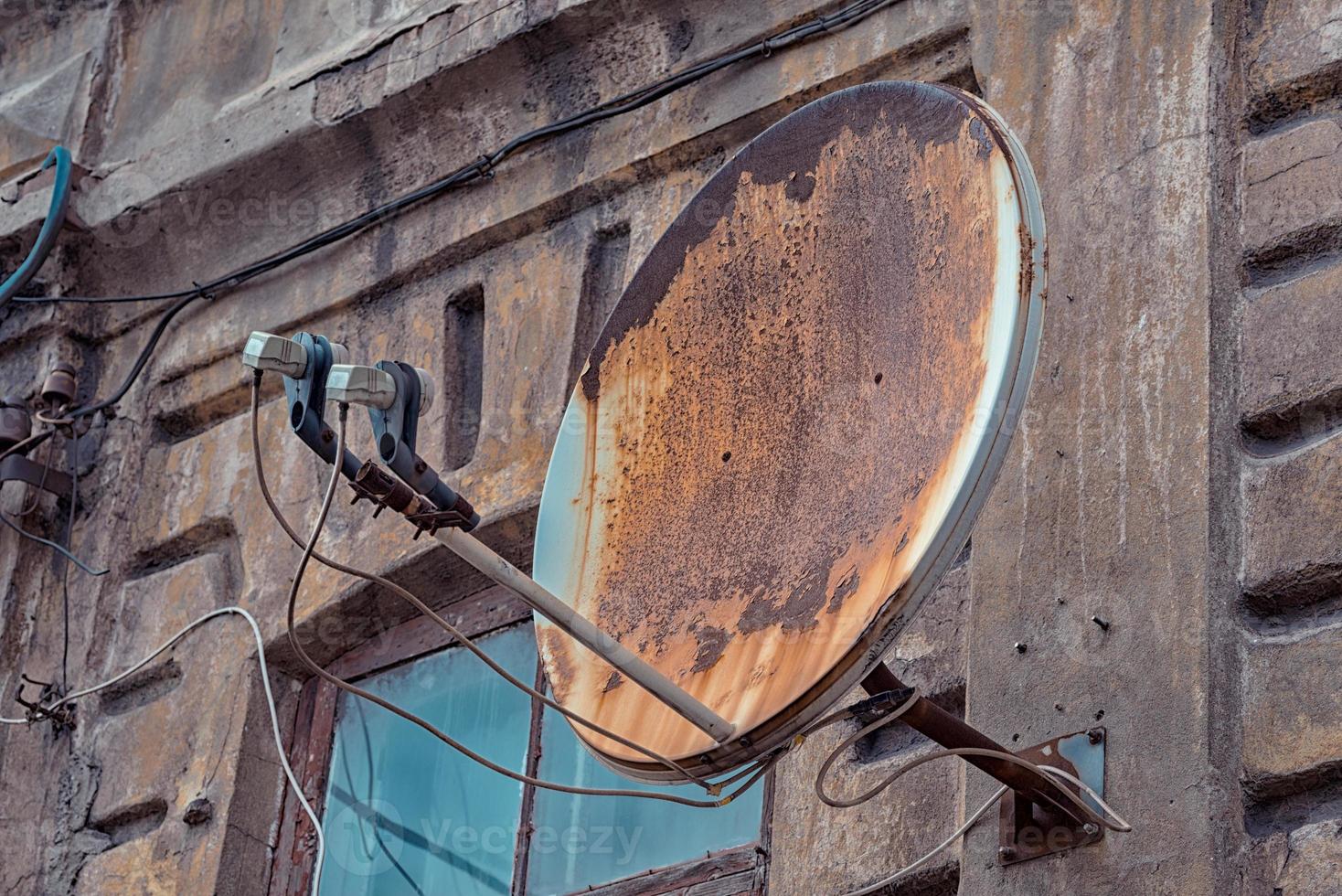antenna parabolica arrugginita su una vecchia casa foto