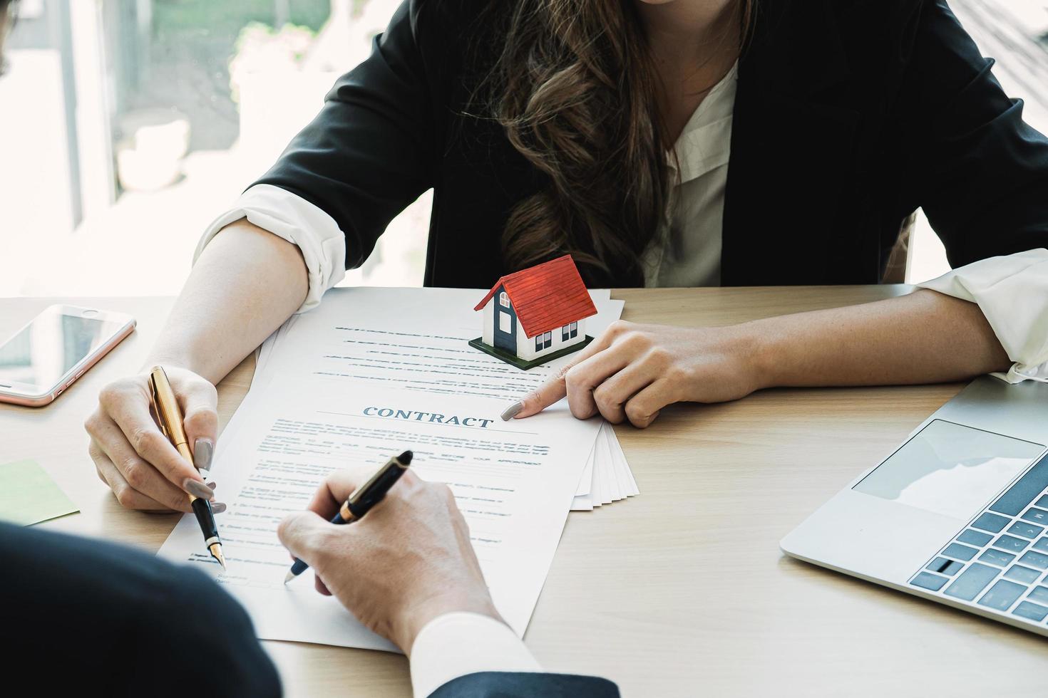 Close up di imprenditrice e cliente che punta e firma un accordo per l'acquisto di una casa. concetto di direttore di banca. foto