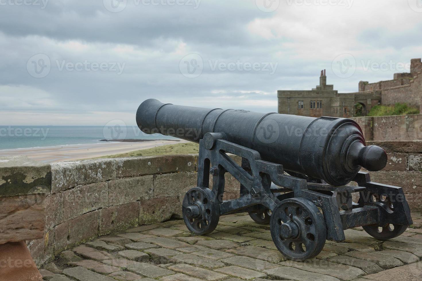Il vecchio cannone di ferro al castello di Bamburgh sulla costa di Northumberland dell'Inghilterra, Regno Unito foto