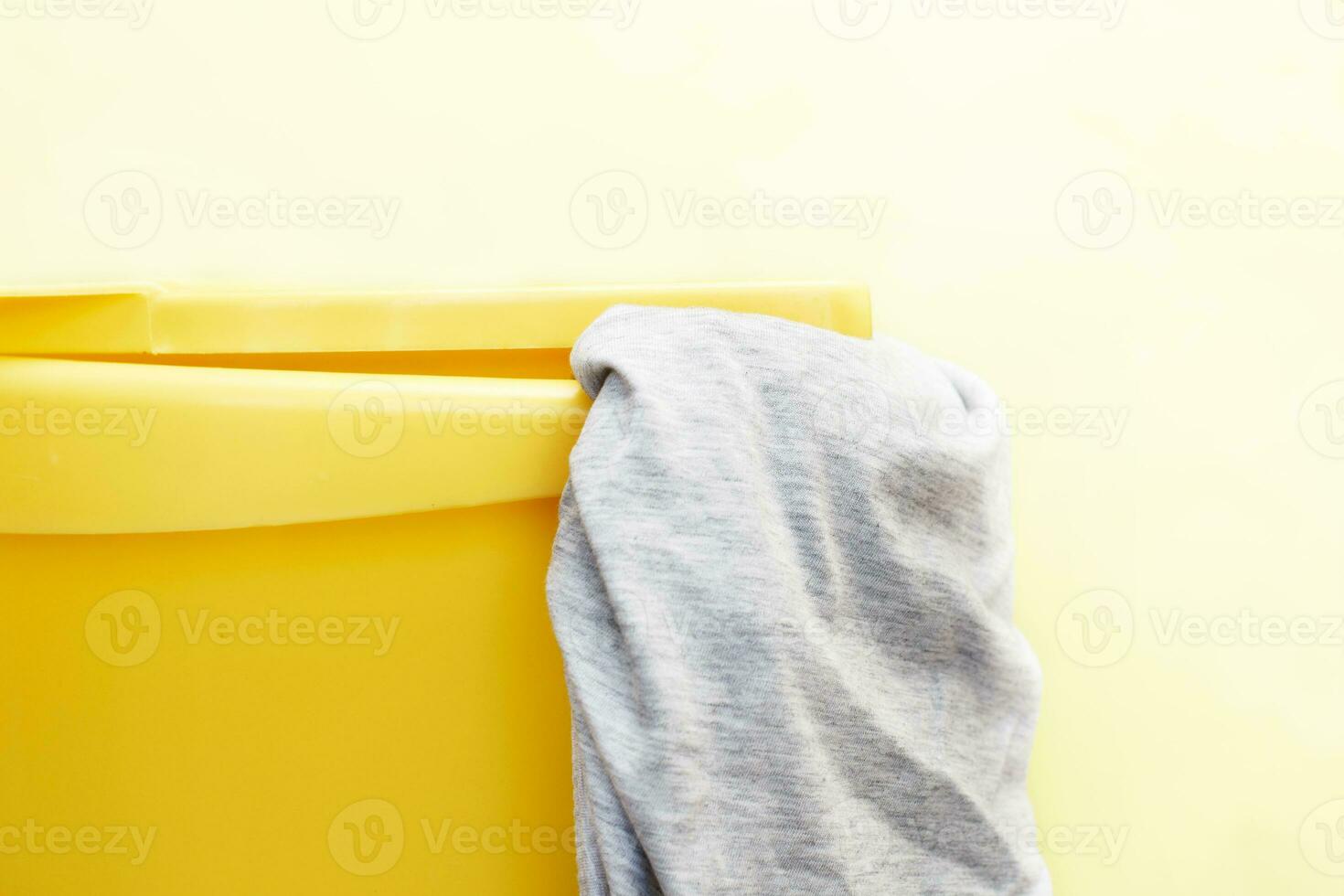 giallo plastica lavanderia cestino con grigio capi di abbigliamento su giallo sfondo foto