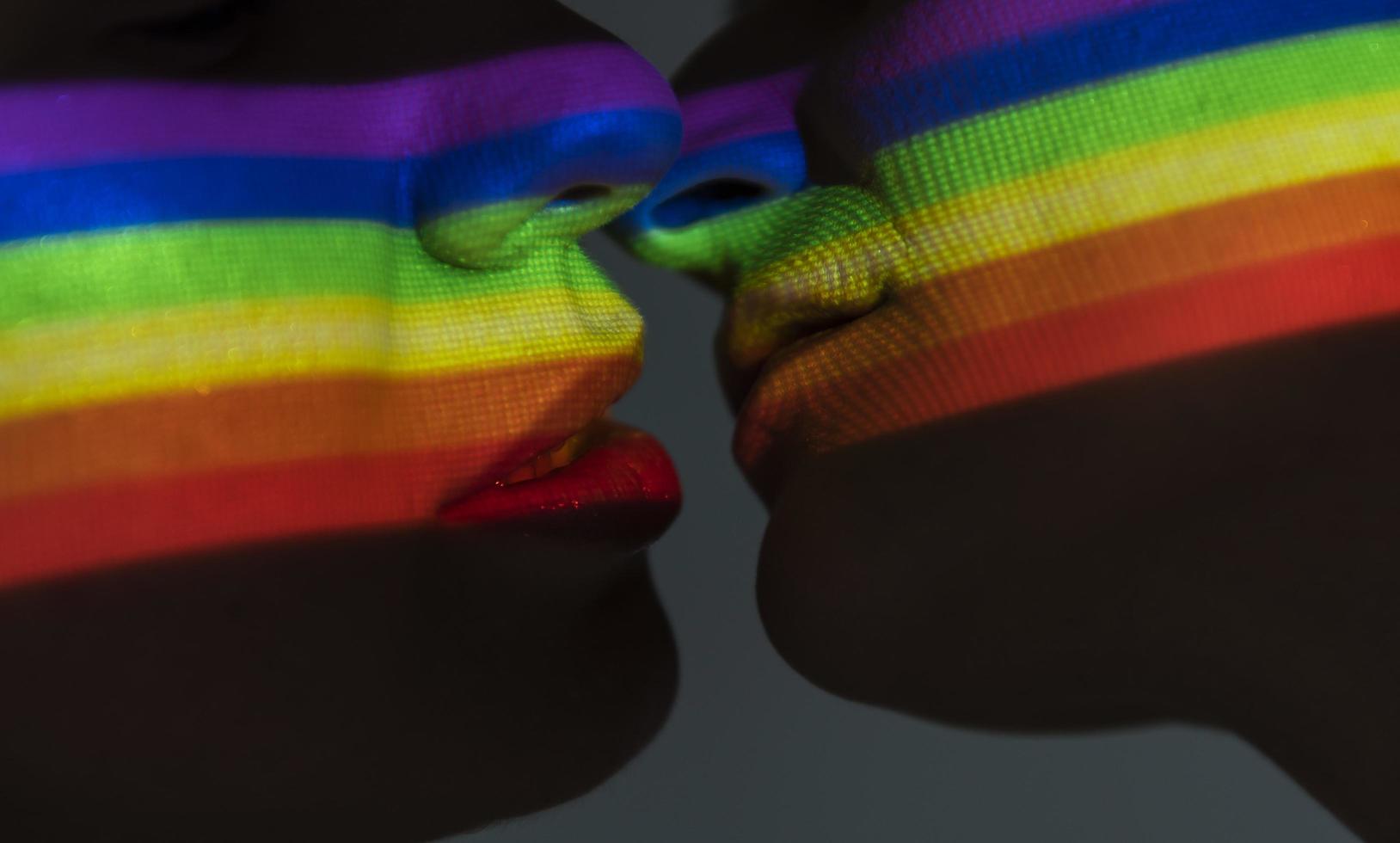 trasparenza della bandiera dell'orgoglio su due persone lgbt che si baciano foto