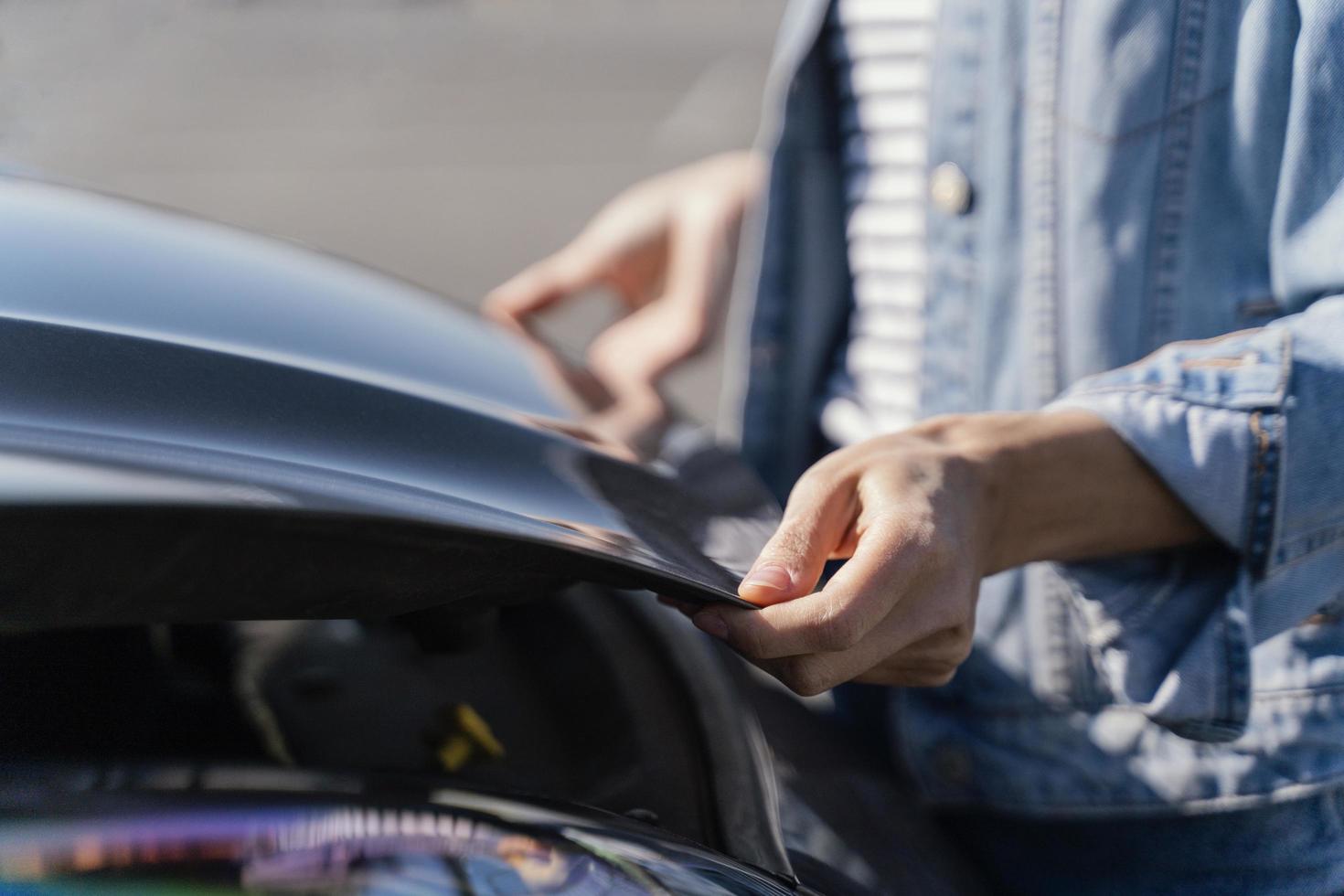 donna che guarda la sua auto per risolvere un problema foto