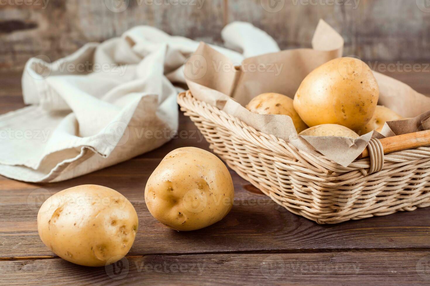 Due tuberi di fresco giallo patate e verdure nel un' cestino e su un' di legno tavolo. vegetariano cibo. foto