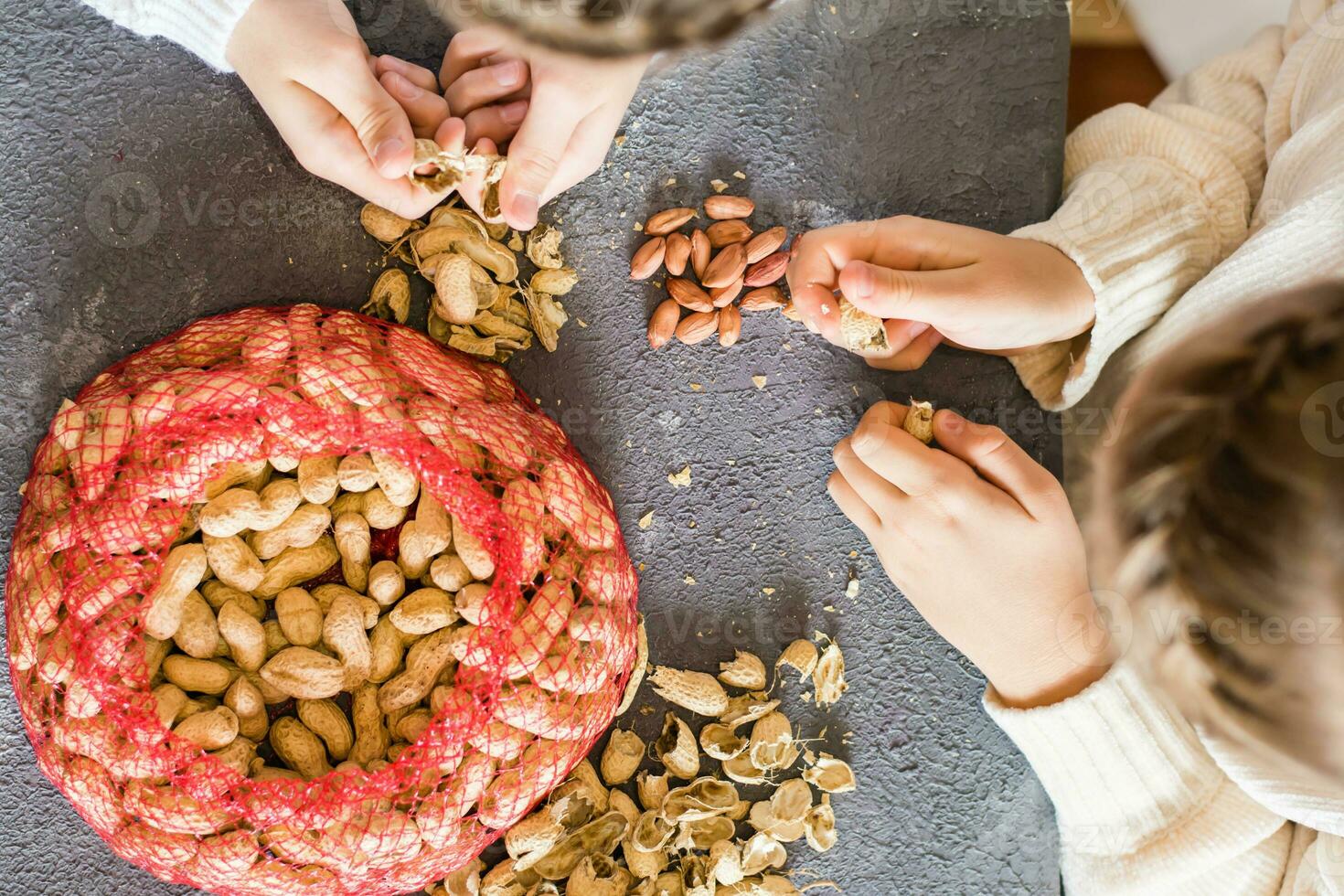 arachide noccioli, un' maglia Borsa con non pelati noccioline e bucce su il tavolo. figli di mani siamo peeling noccioline. stile di vita. superiore Visualizza foto