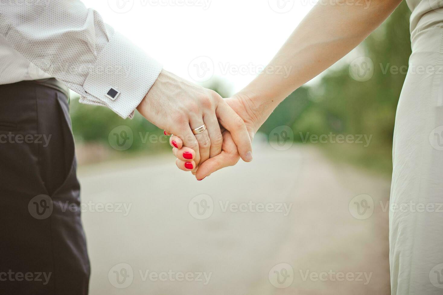 un' uomo detiene un' donna di mano. mani di il sposa e sposo con un' nozze squillare avvicinamento foto