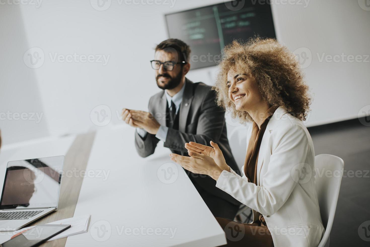 gruppo multietnico di uomini d'affari che lavorano insieme e che applaudono dopo un incontro di successo in ufficio foto