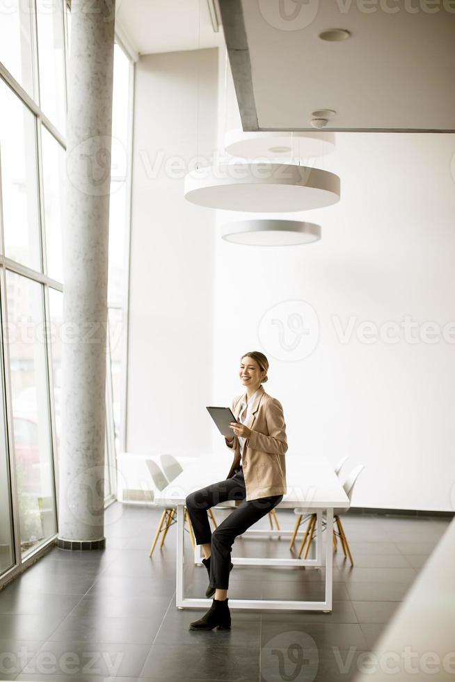 giovane donna che tiene tavoletta digitale in ufficio moderno foto