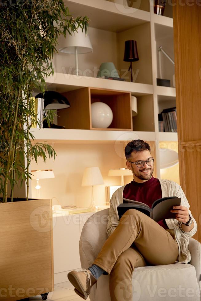 bel giovane in abiti casual e con gli occhiali da vista leggendo un libro foto