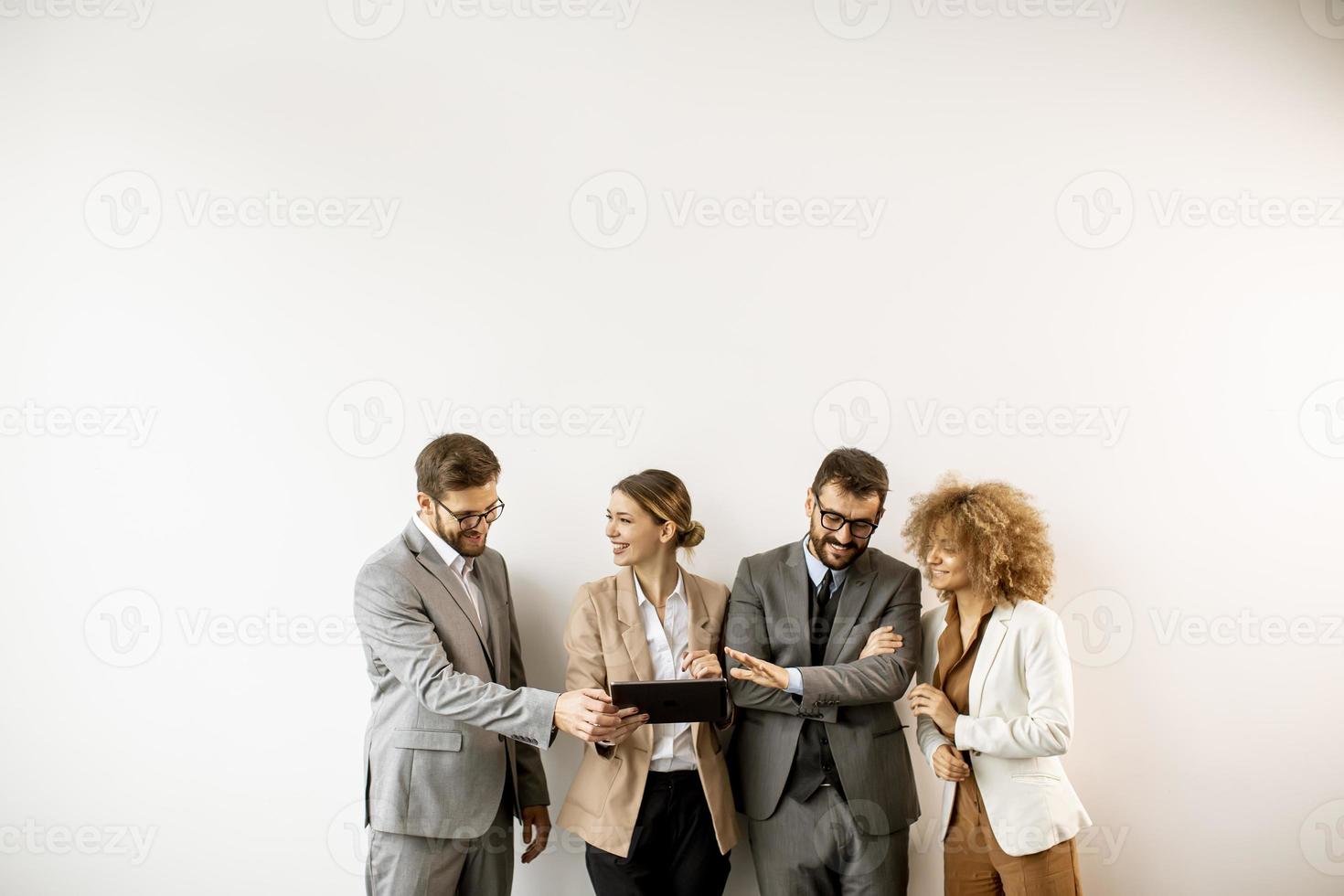 uomini d'affari multietnici utilizzando la tavoletta digitale in piedi vicino al muro in ufficio foto