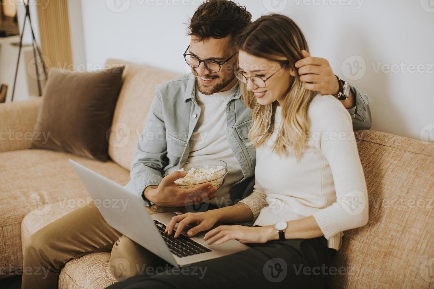 giovane coppia utilizzando laptop insieme mentre è seduto sul divano di casa foto