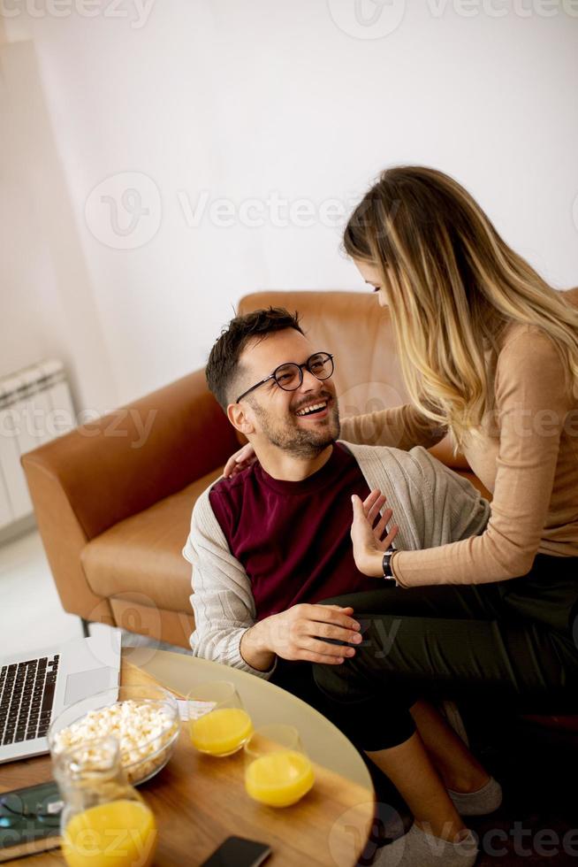 giovane donna e giovane uomo utilizzando laptop mentre è seduto dal divano di casa foto