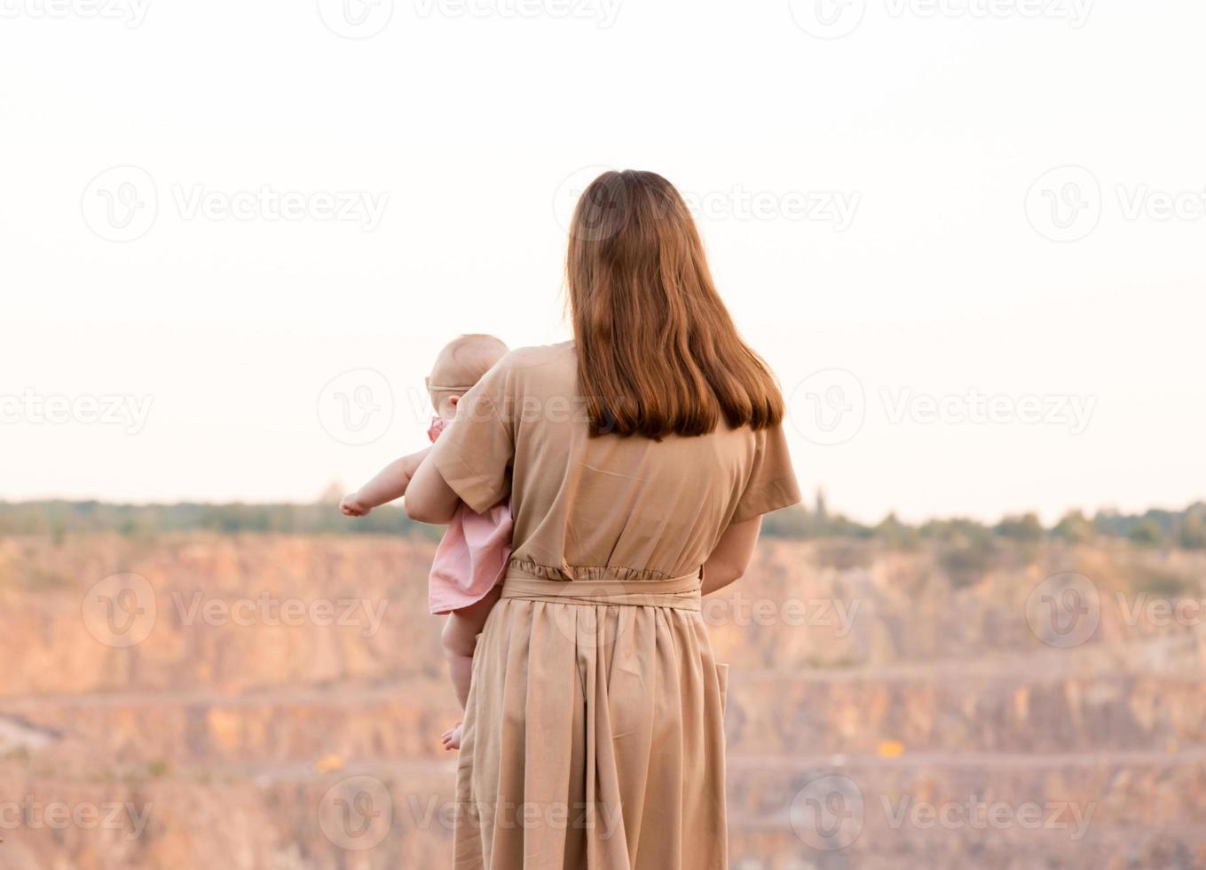 una giovane madre sta guardando la cava o le montagne e tiene in braccio un bambino foto