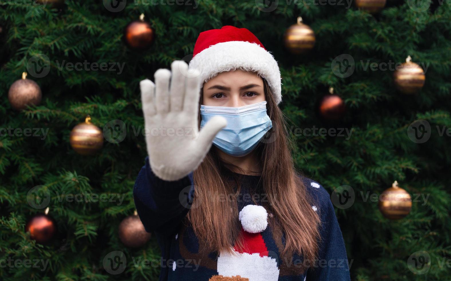 Close-up ritratto di donna che indossa un cappello di Babbo Natale e mascherina medica con emozione foto