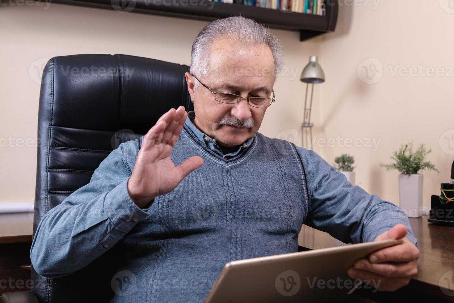 uomo anziano leggendo notizie sulla tavoletta digitale foto