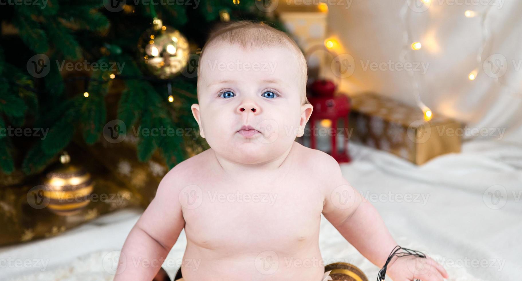 bambino nudo sul pavimento nella stanza di Natale decorata foto
