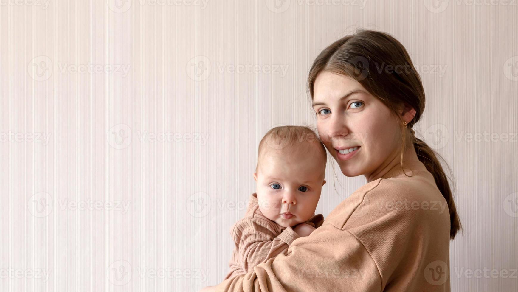 una giovane madre tiene in braccio una bambina di 3 mesi foto
