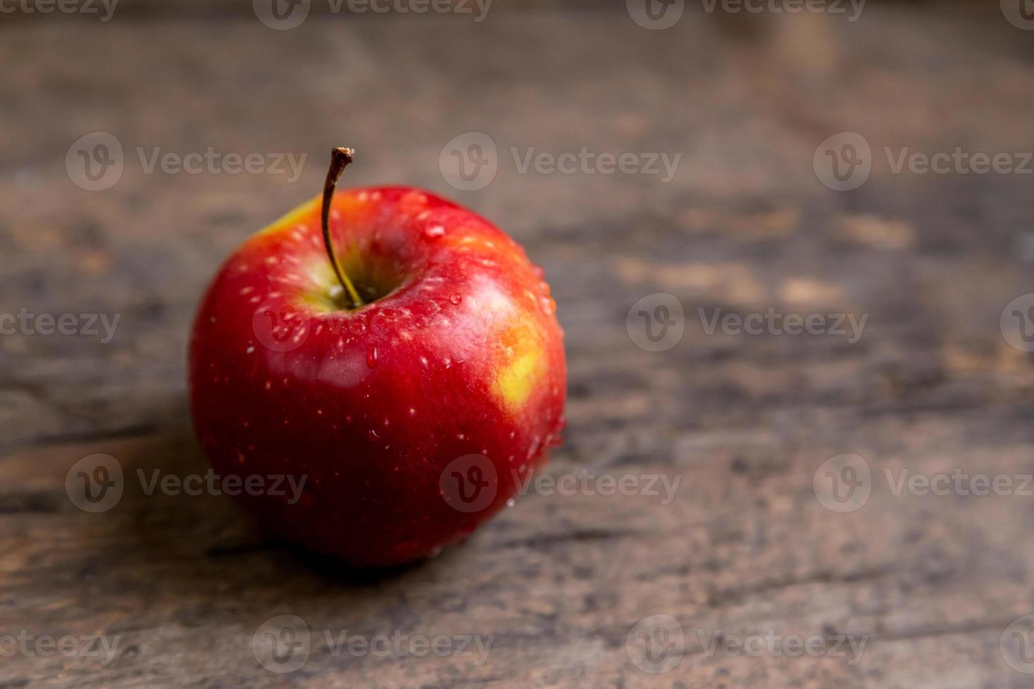 una mela con gocce d'acqua posta sul tavolo di legno foto