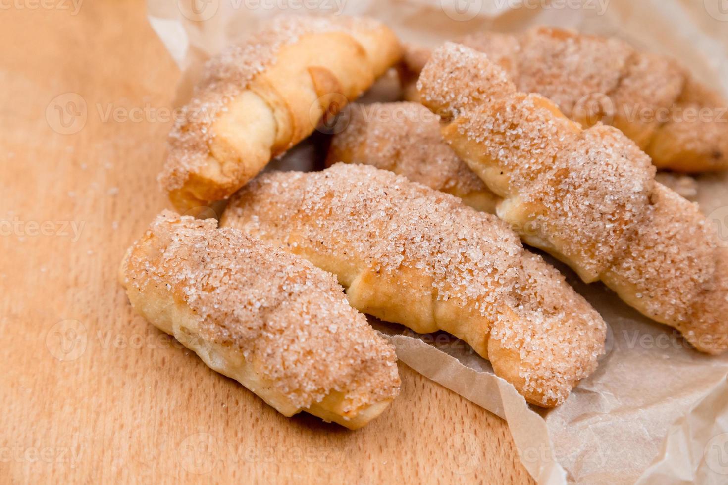 croissant freschi con cannella su carta spiegazzata su fondo in legno tavolo foto