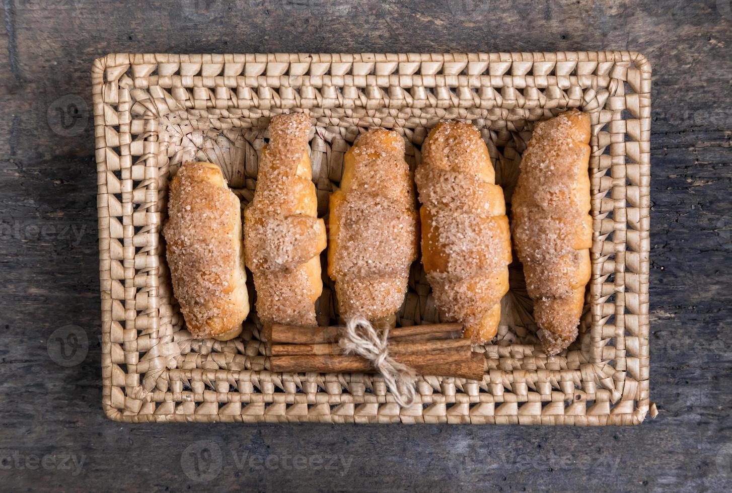 i croissant giacciono in un cesto di vimini con cannella foto