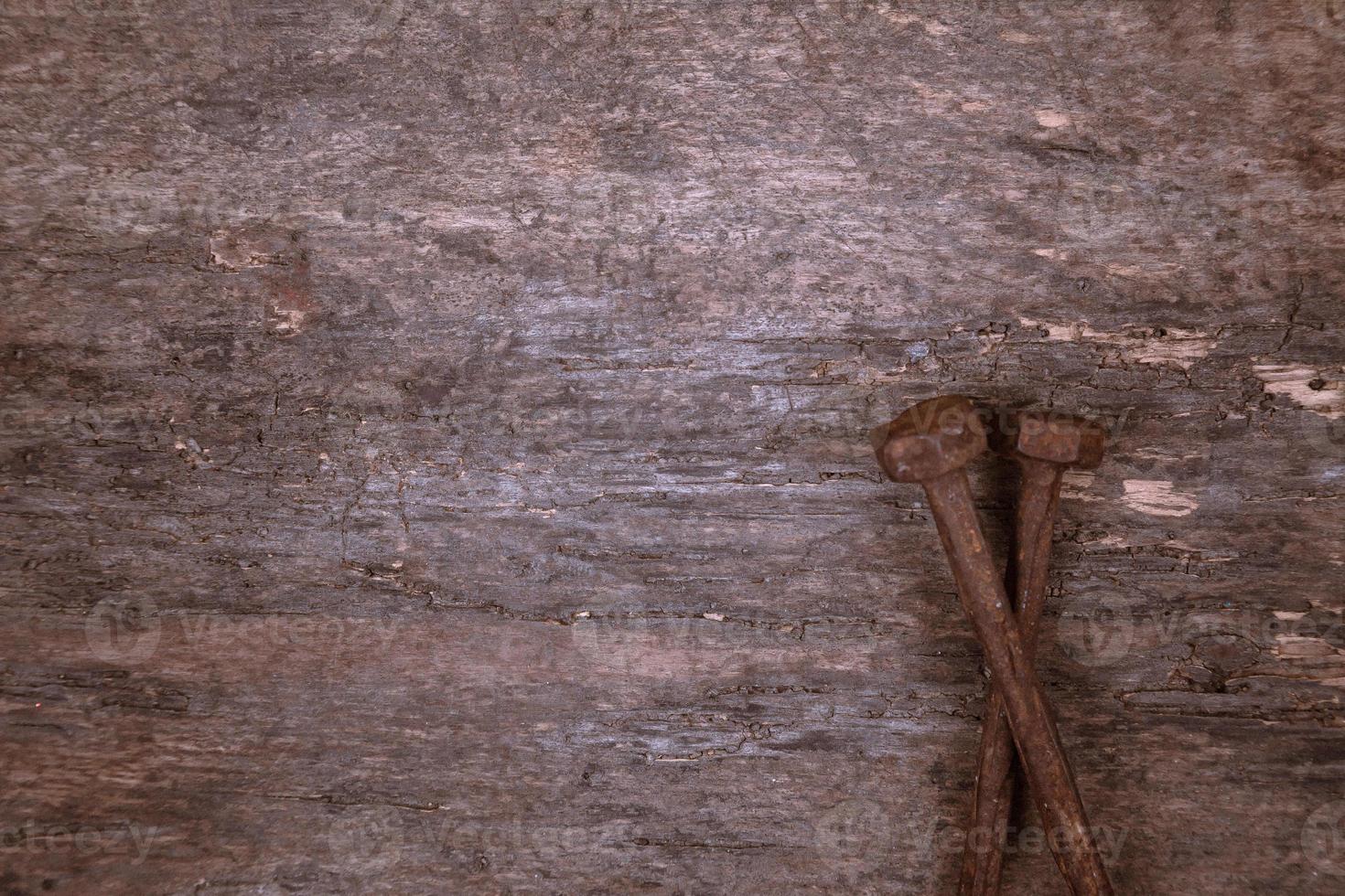 due vecchi chiodi arrugginiti poggiano su uno sfondo di legno foto