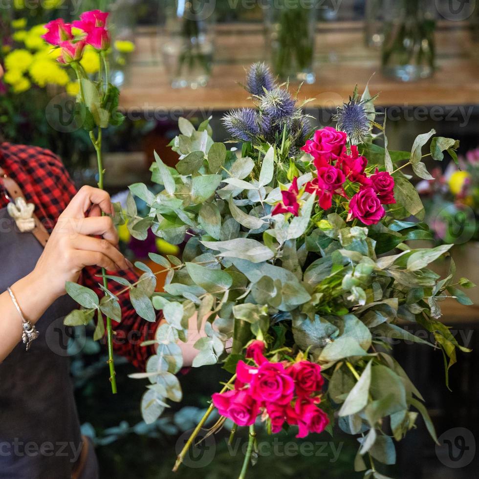 donna fioraio che fa bouquet di fiori presso il negozio foto