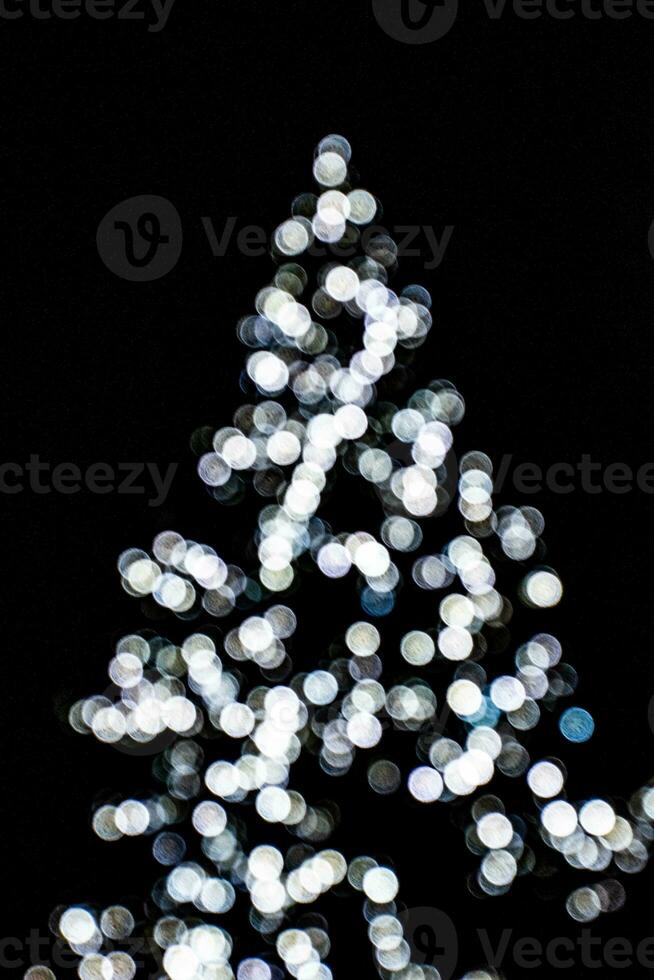 sfocato luci illuminante il Natale albero su un' nero sfondo foto