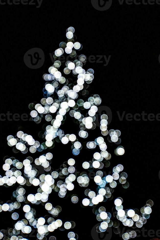 sfocato luci illuminante il Natale albero su un' nero sfondo foto