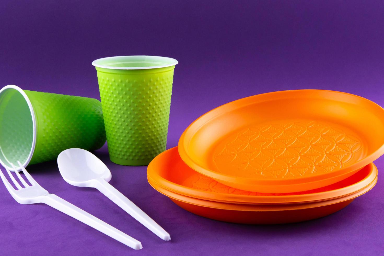 raccolta dei rifiuti di plastica arancione e verde su sfondo viola foto