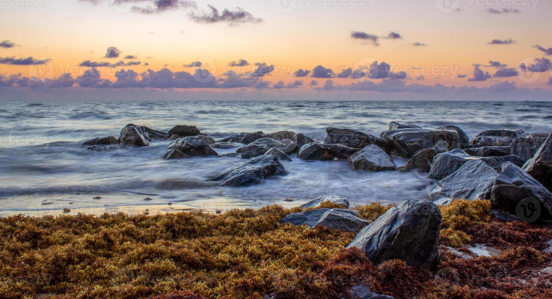 rocce nere accanto allo specchio d'acqua all'ora d'oro foto