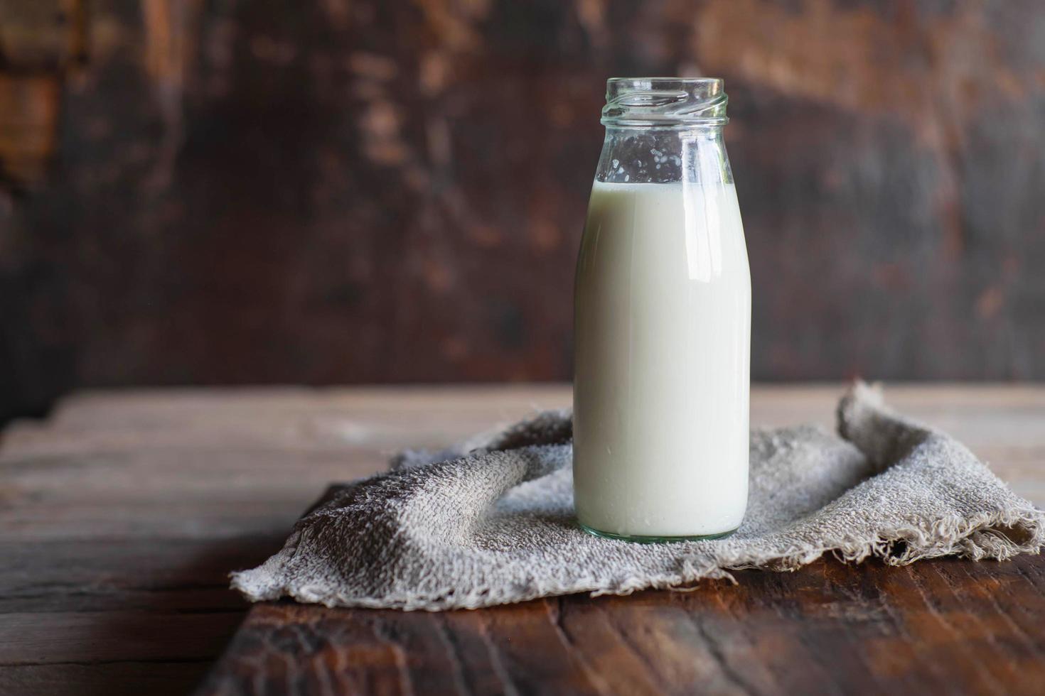 una bottiglia di latte fresco su un tavolo di legno foto