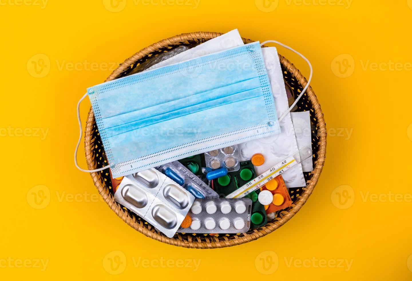 cesto di vimini pieno di forniture mediche e farmaci su sfondo giallo foto