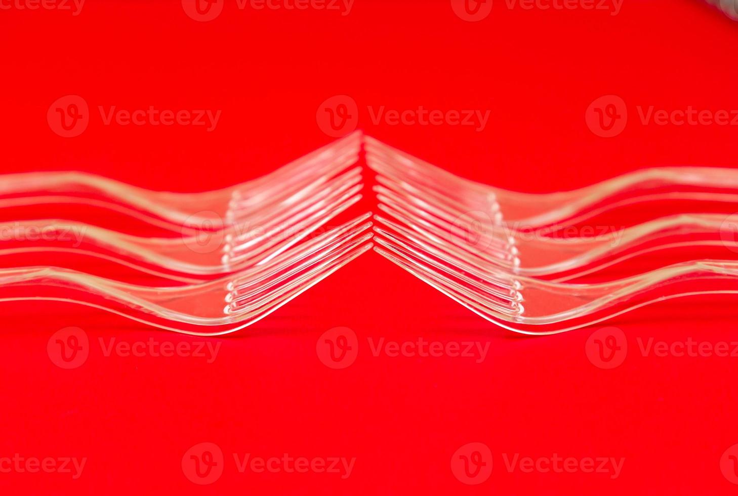 Close-up di forchette di plastica trasparente su uno sfondo rosso foto