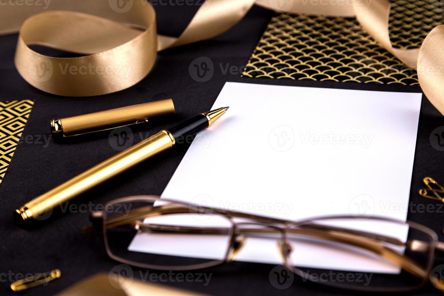 graffette e cancelleria nastro penna d'oro su sfondo nero con un foglio di carta bianco con spazio di copia foto