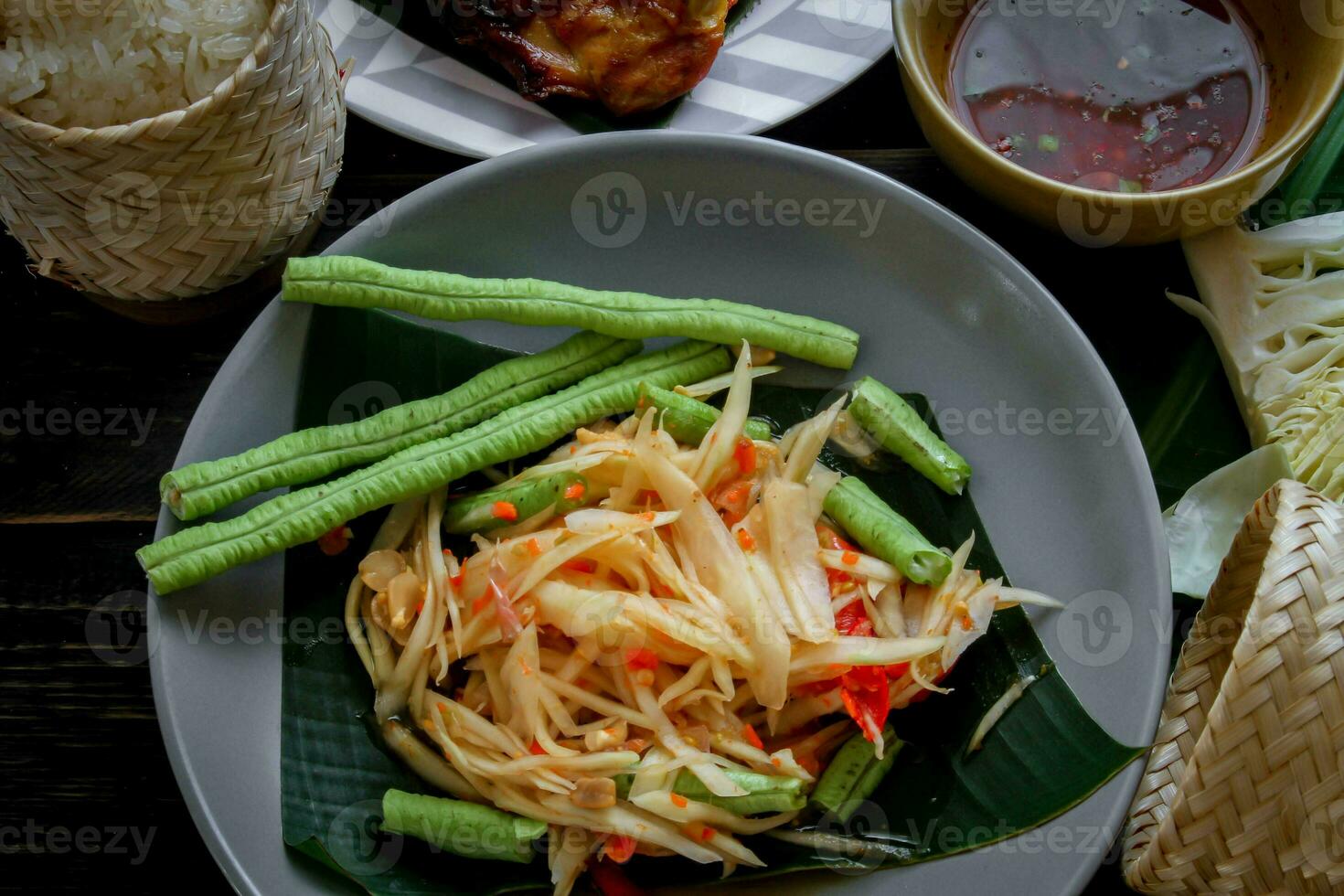 tailandese cibo piatto tutti e due nel Tailandia e Asia papaia insalata o come noi chiamata esso somtum è integrato con grigliato pollo e appiccicoso riso con fresco patatine fritte. servito su il nero di legno tavolo. foto