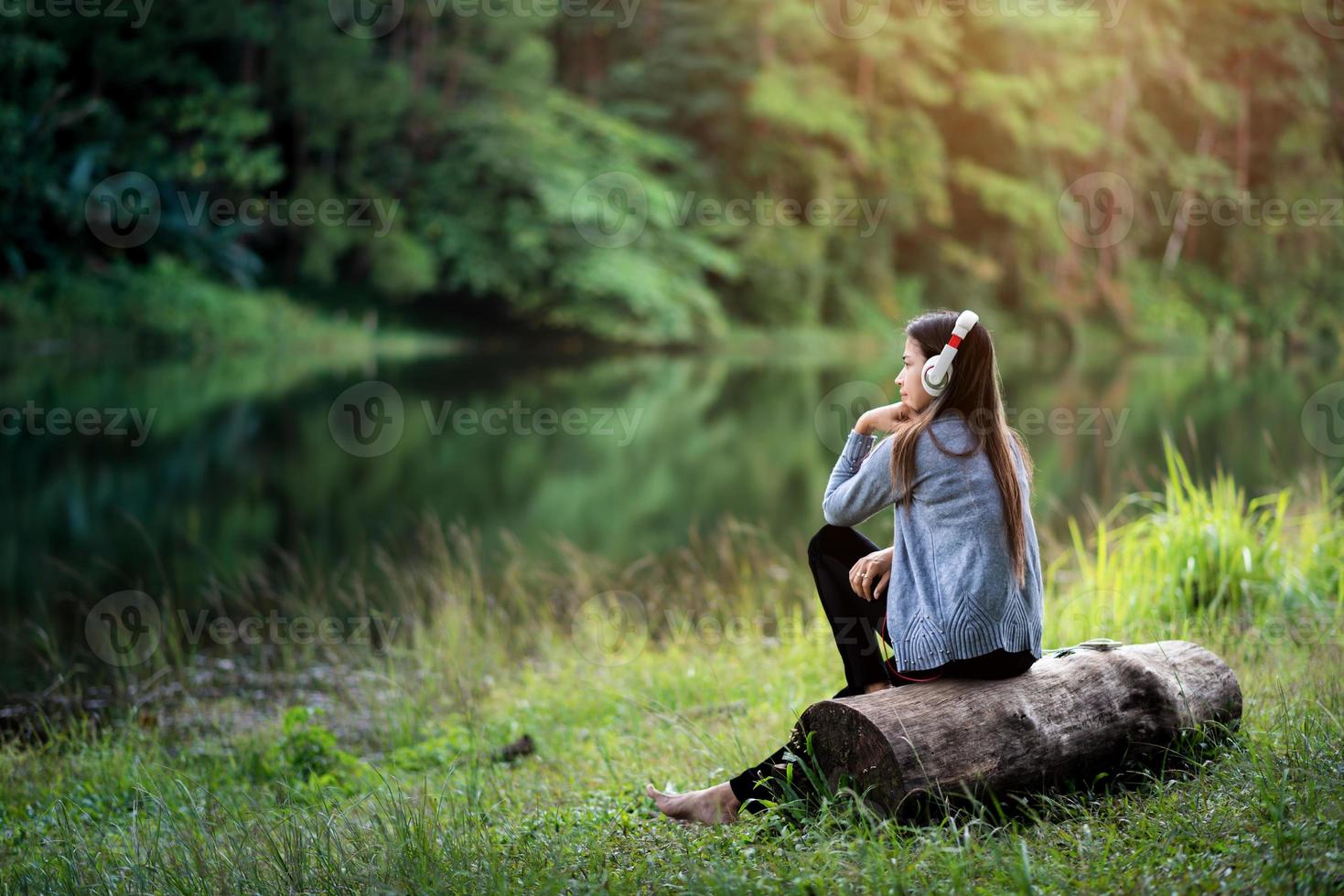 bella giovane donna con le cuffie che si distendono vicino al fiume foto