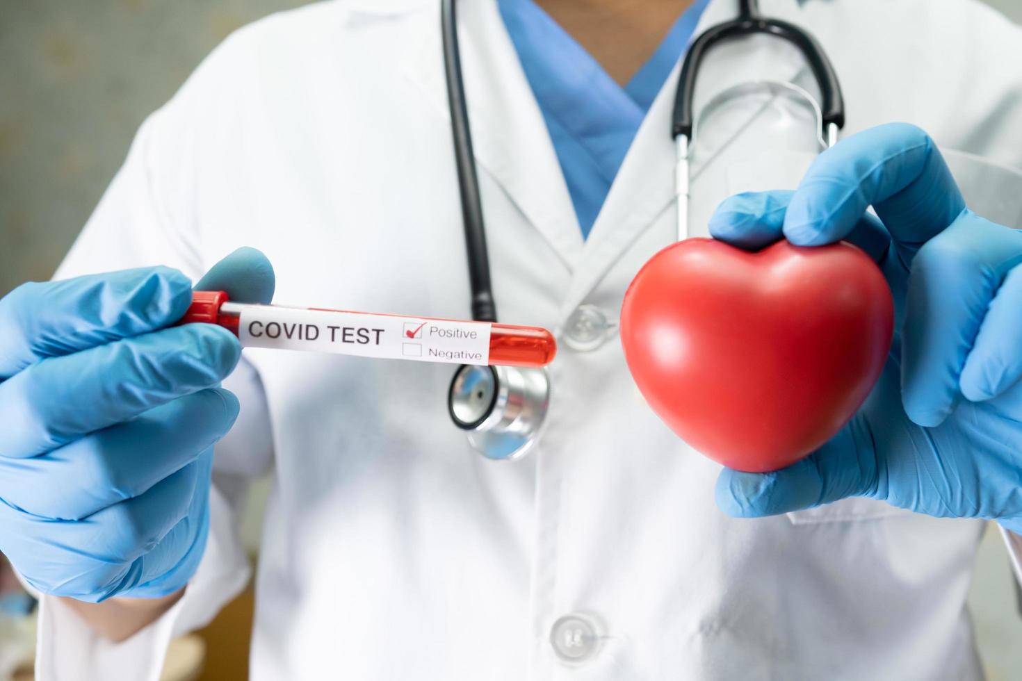 campione di infezione del sangue positivo in provetta per il coronavirus covid 19 nello scienziato di laboratorio che tiene un cuore rosso per incoraggiare il paziente in ospedale foto