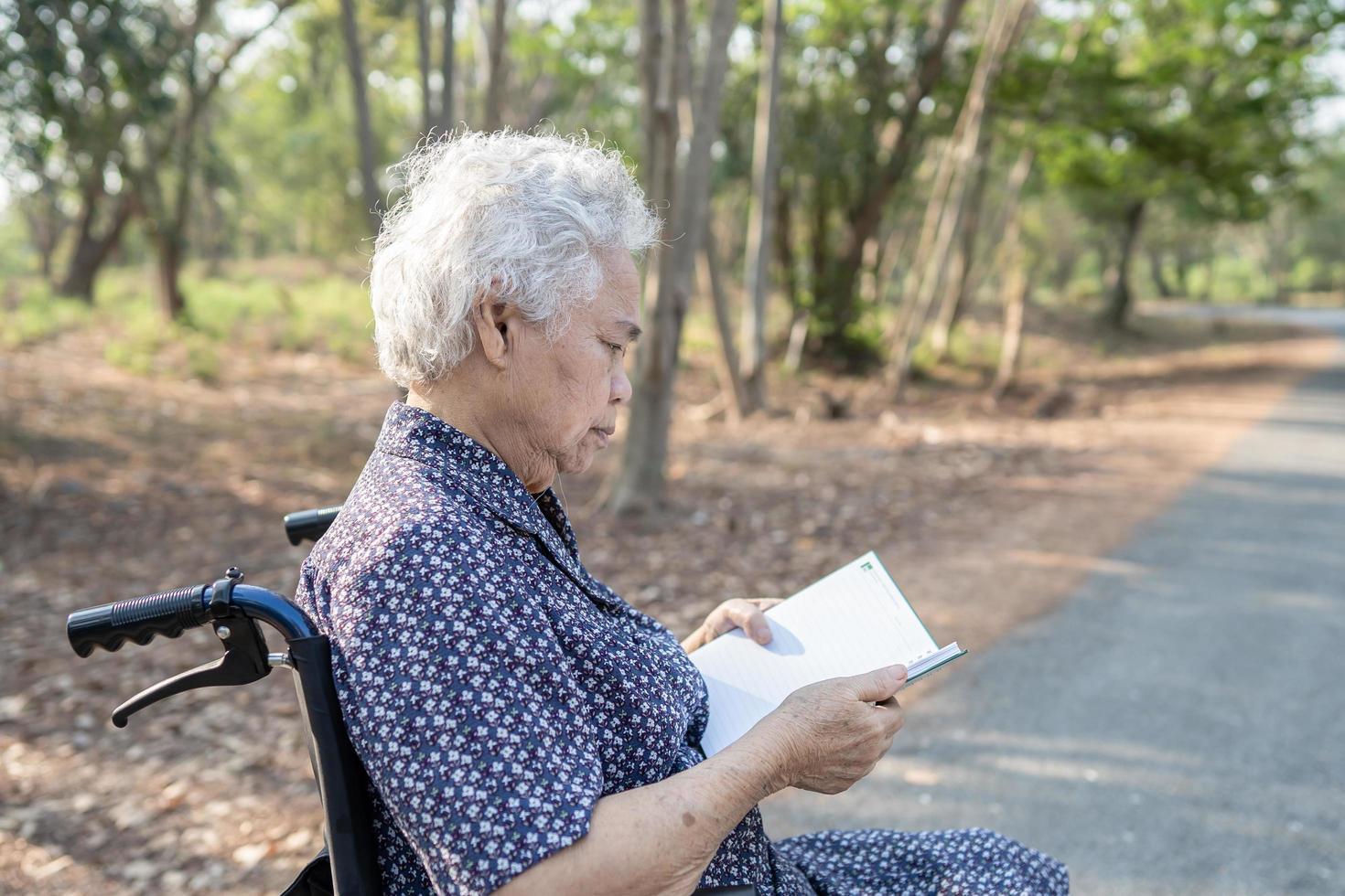 paziente asiatico anziano o anziano della donna della signora anziana che legge un libro mentre si sedeva sul letto nel concetto medico sano del reparto di cura dell'ospedale forte foto