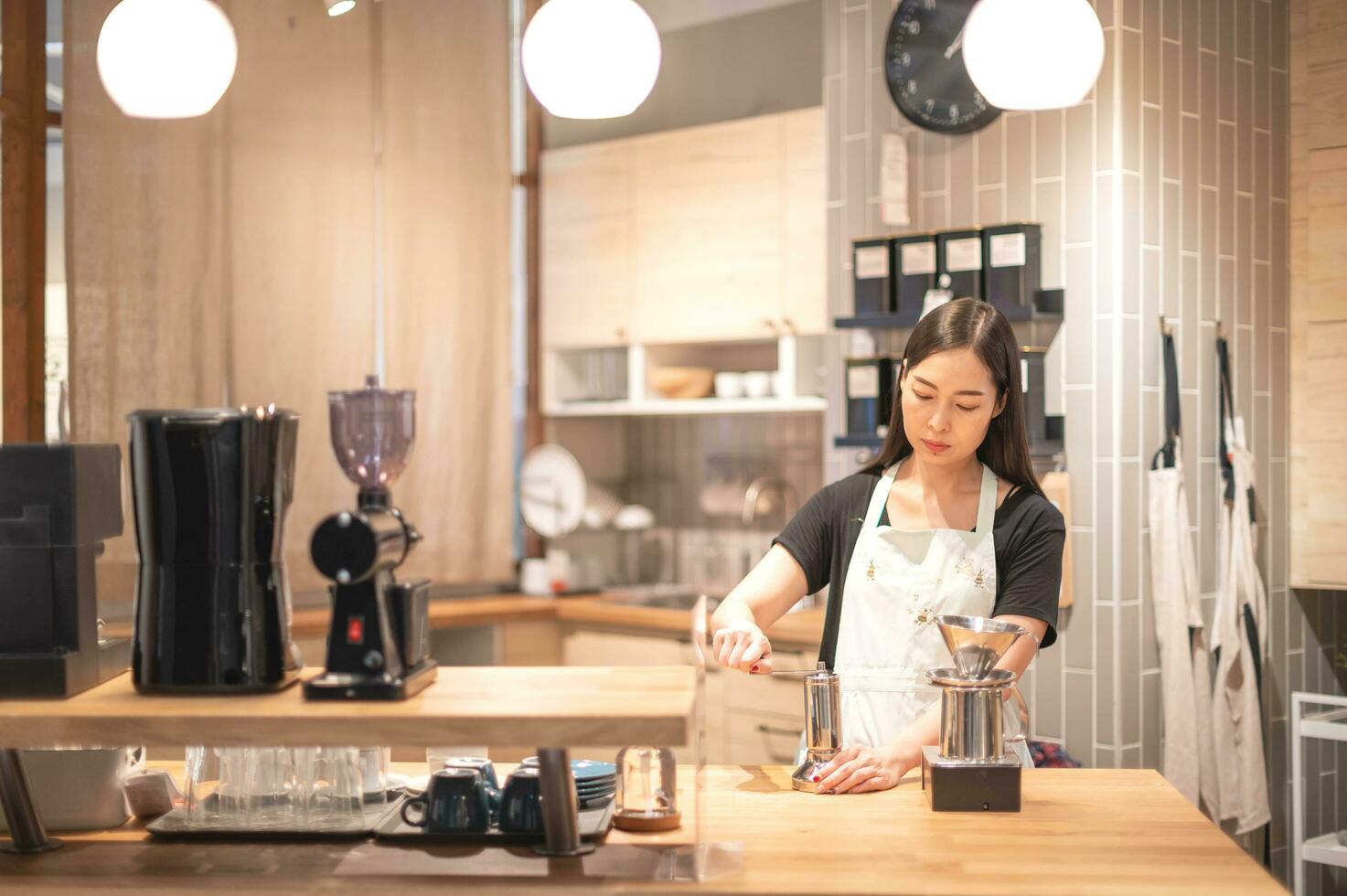 femmina mano miscuglio caffè fagiolo nel caffè macinino su di legno tavolo. foto