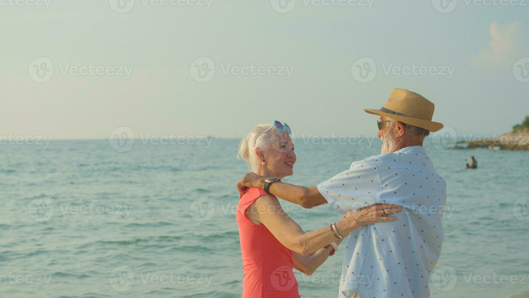 Due anziano uomini e donne danza a il spiaggia su loro estate vacanza e essi Sorridi e godere loro giorno spento. foto