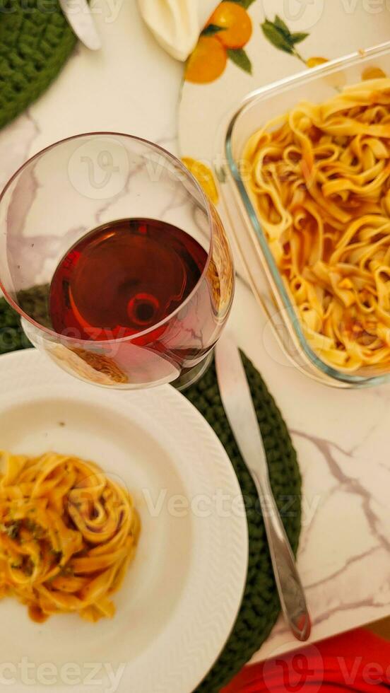 cena con pasta e bicchiere di rosso vino foto