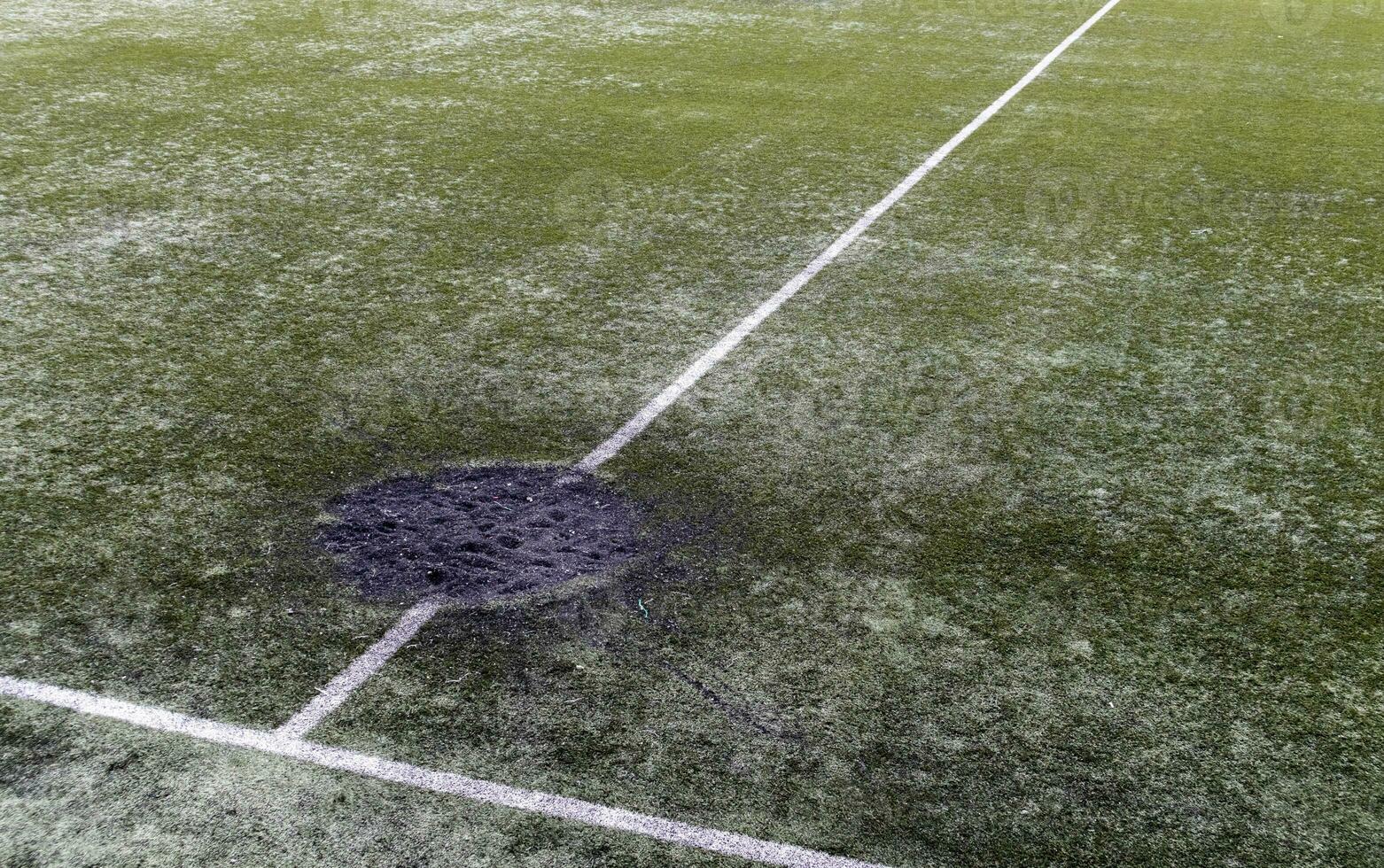 un' buco nel il terra a partire dal un' cannone conchiglia esplosione pieno con fresco terra a un' calcio stadio. bombardamento cratere nel il città. terreno di gioco. guerra nel Ucraina. distruzione di civile infrastruttura. foto