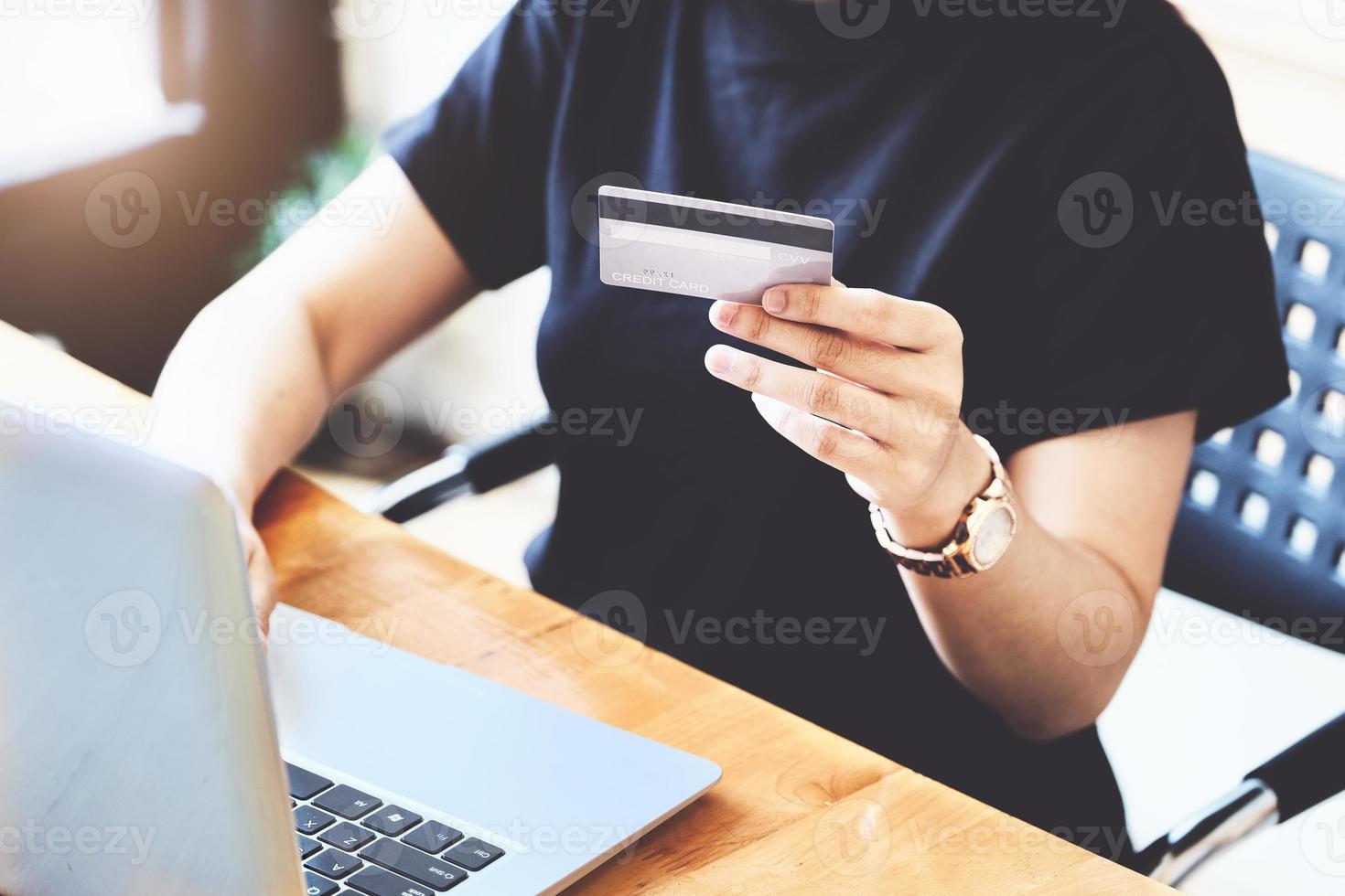 giovane donna in possesso di carta di credito e l'utilizzo del computer per lo shopping online foto