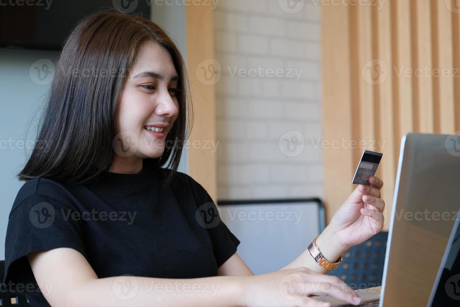 giovane donna in possesso di carta di credito e l'utilizzo del computer per lo shopping online foto