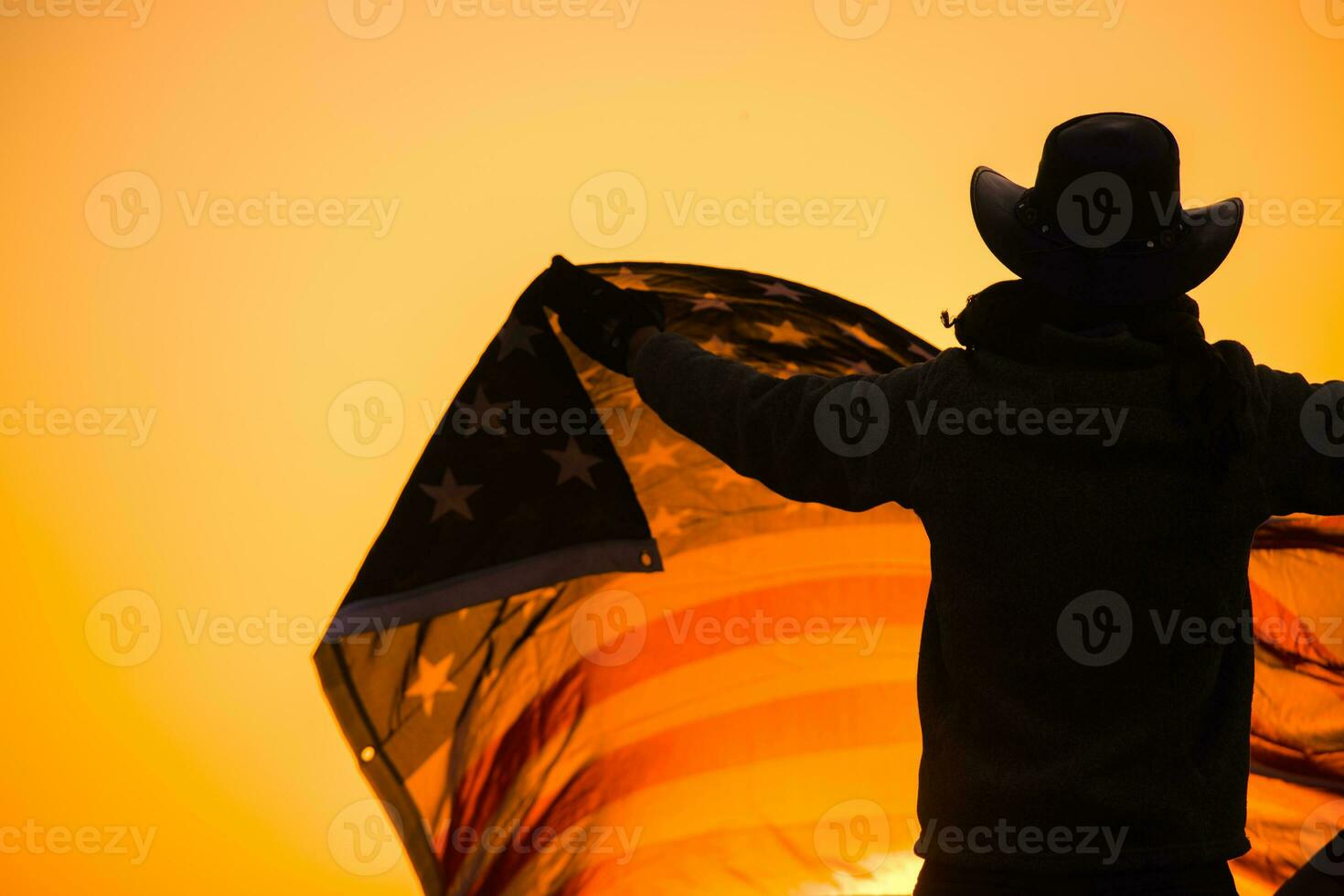 uomo nel un' cowboy cappello agitando un americano bandiera a tramonto foto