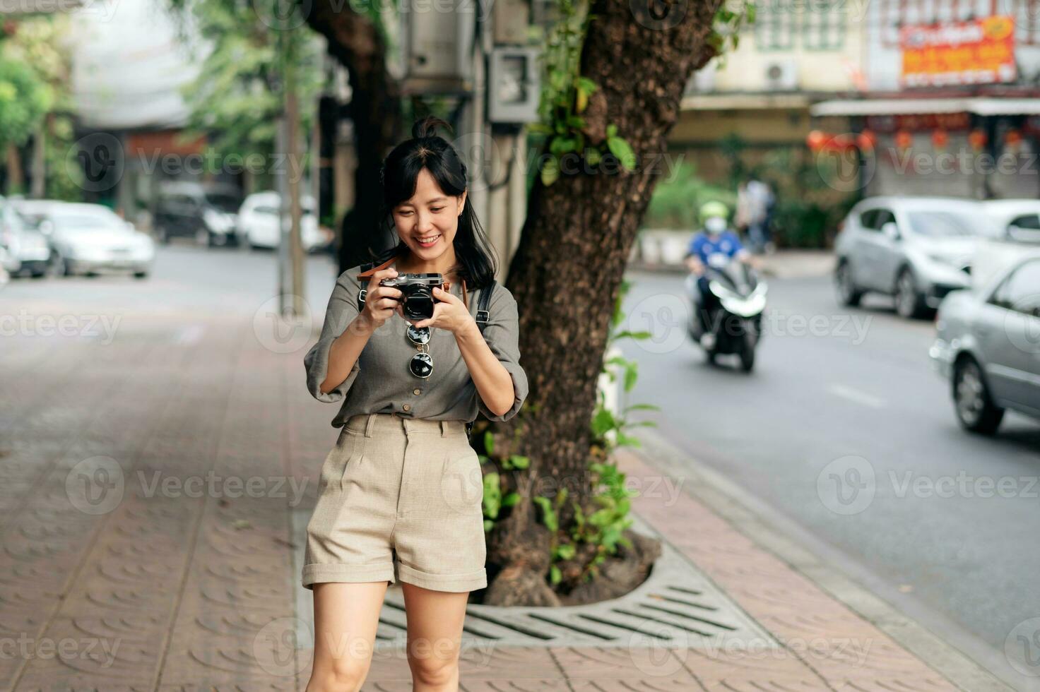 giovane asiatico donna zaino viaggiatore utilizzando digitale compatto telecamera, godendo strada culturale Locale posto e Sorridi. viaggiatore controllo su lato strade. foto