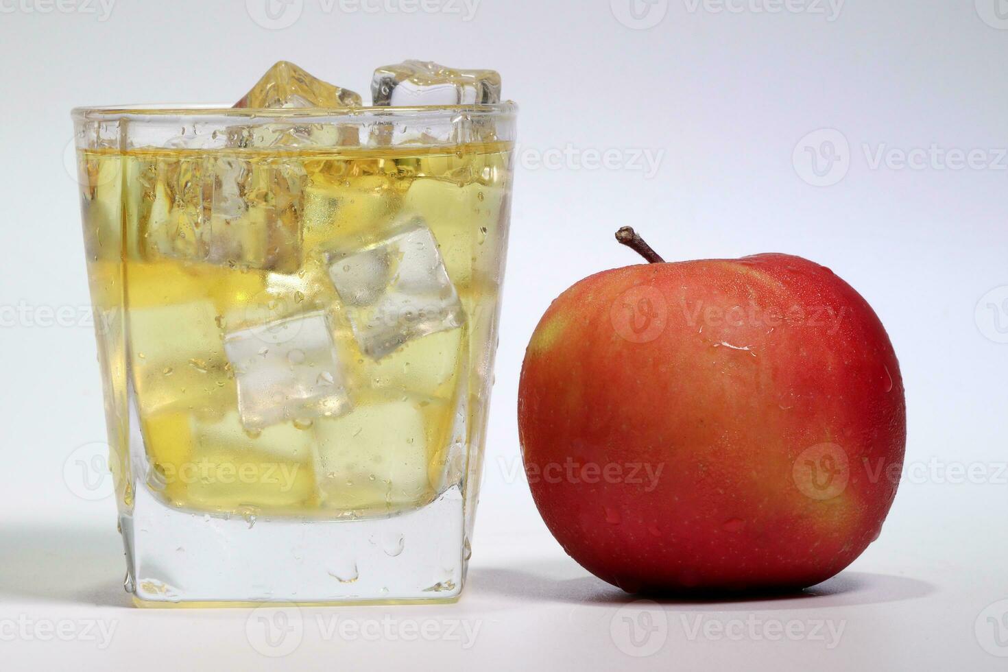 Mela succo gocciolante fluente attraverso smerigliato bicchiere ghiaccio cubo foto